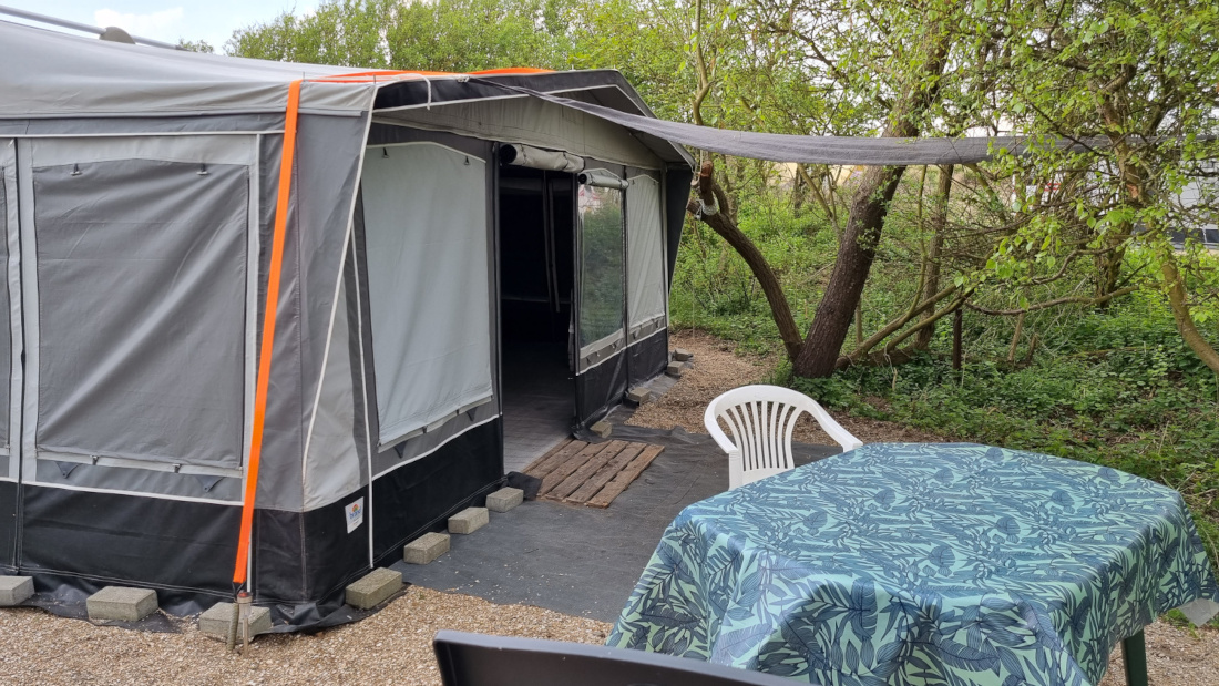 Beschut tegen de zon zitten voor de caravan